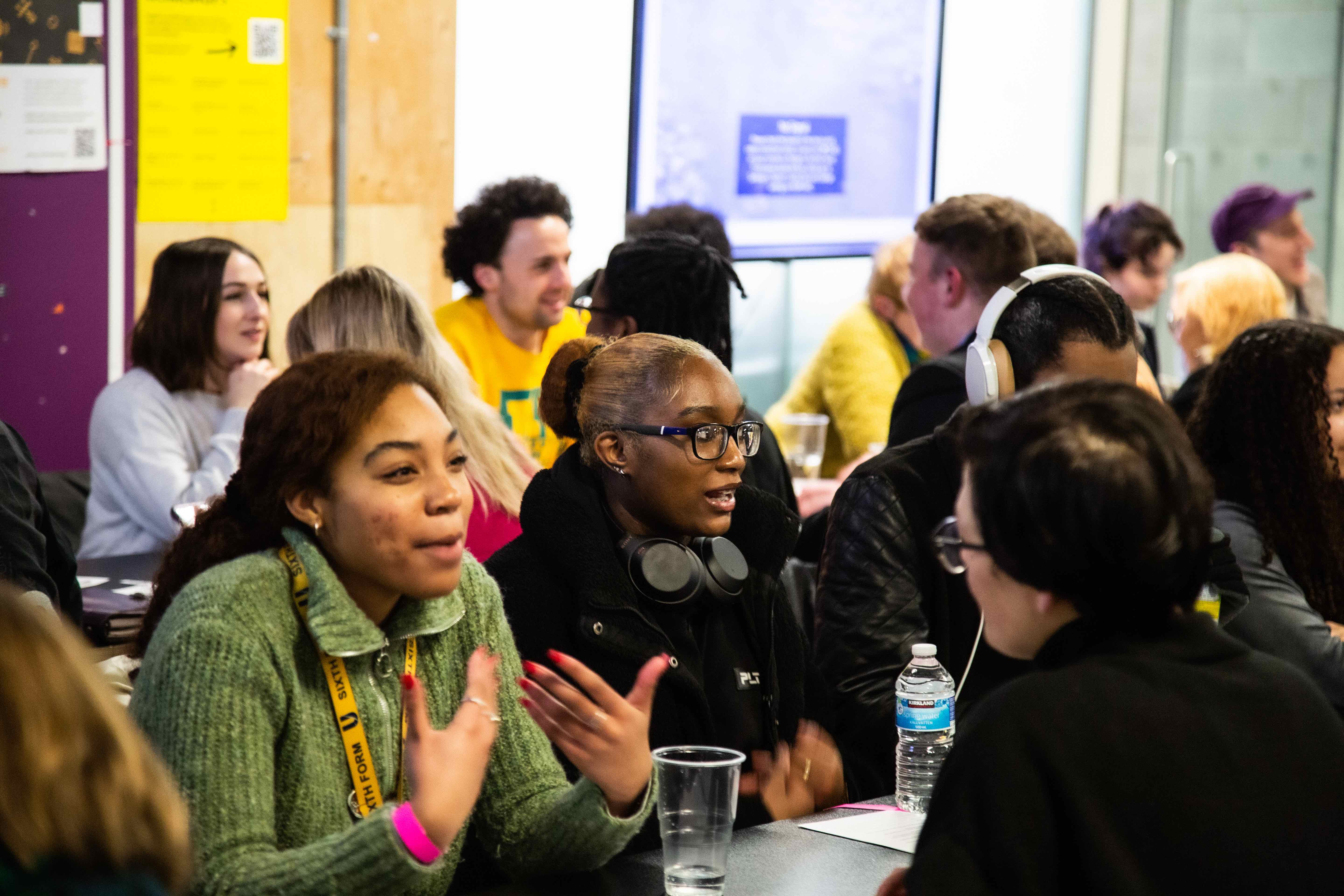 Young people at a meeting with their mentors speaking across desks.