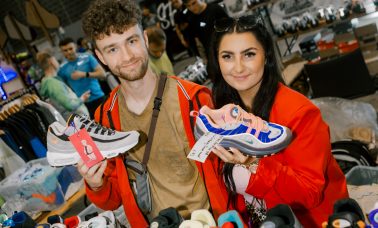 Two people holding sneakers at a sneaker convention.